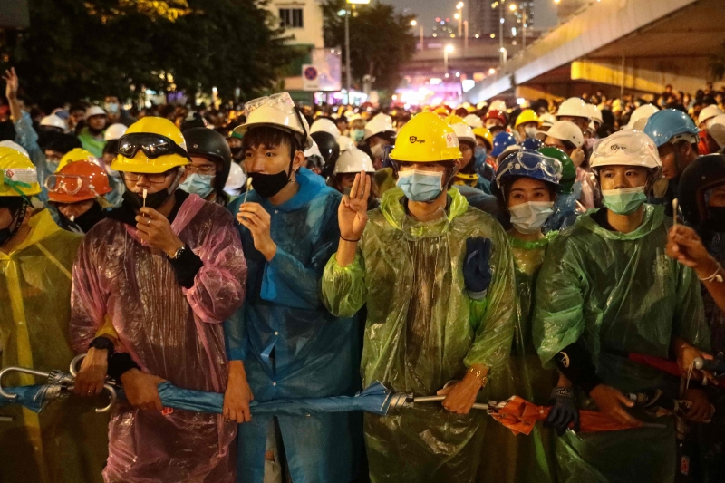 抗议者身穿雨衣和带头盔，朝着警方行三指礼表示抗议。（法新社照片）