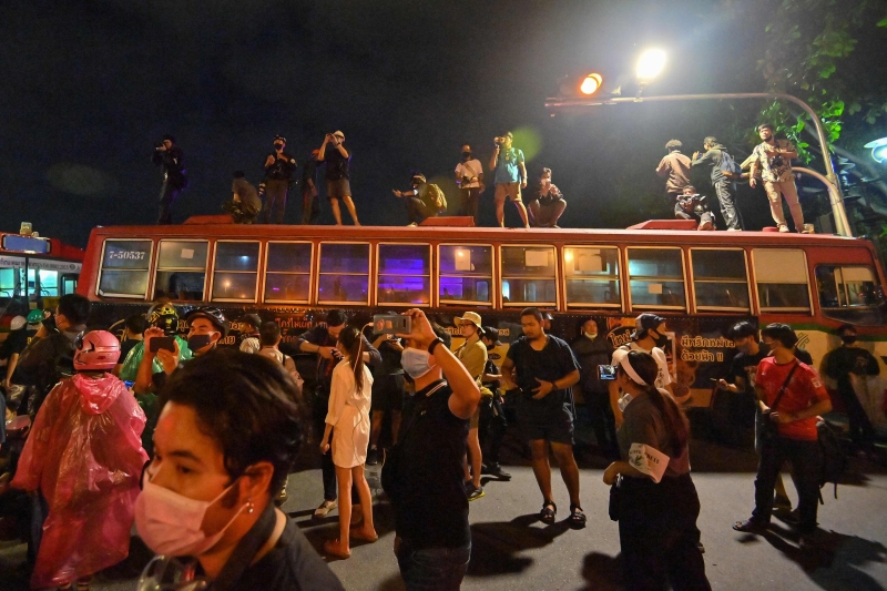 一些示威者和新闻工作者爬上位于曼谷街道上巴士车顶。（法新社照片）