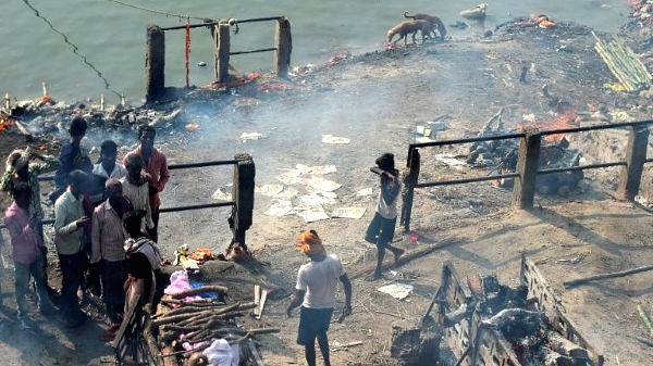 A young boy (R) looks for discarded clothes used to wrap dead bodies for final rites for money, at a cremation site in Varanasi. AFP