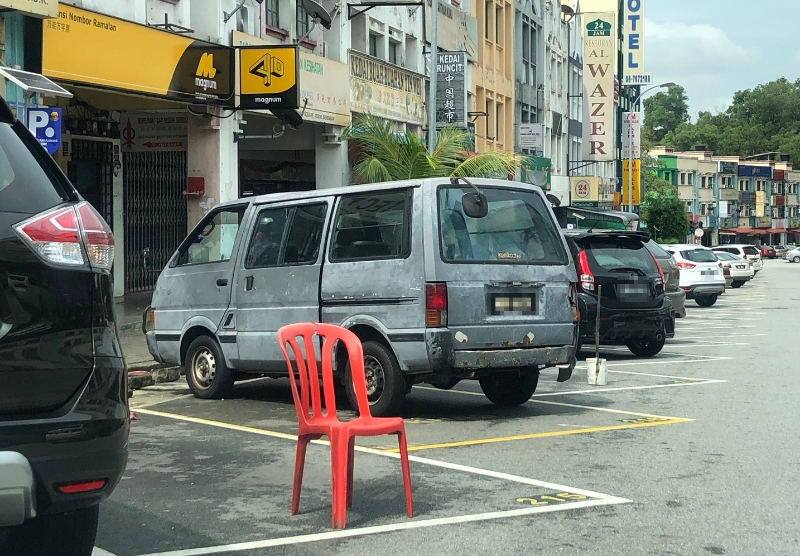 商家为了预留泊车位给顾客，使用椅子霸占停车位。（档案照）
