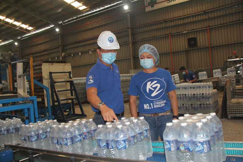 廖显光（左）及陈俐伶（右）一同检视饮用水生产线操作。