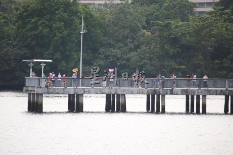 为了不错过约定好的相会时间，家人一早就站在新加坡兀兰海滨公园，也有者举起看板，表达思念之情。