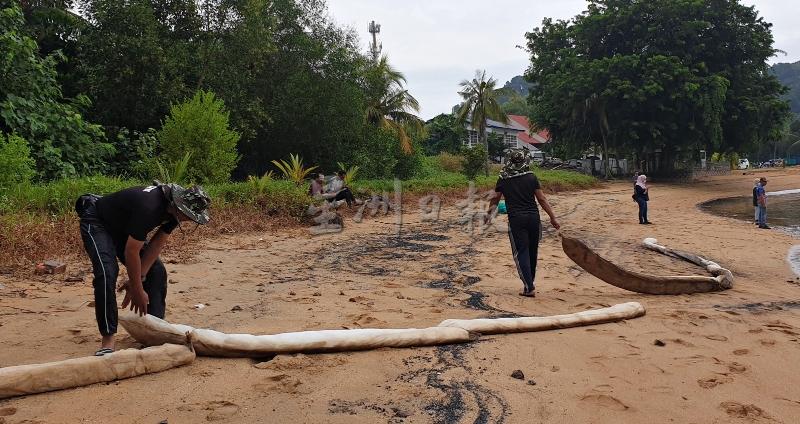 随着清除污油工作来到了尾声，工作人员将装置在沙滩上的索状吸油棉回收。