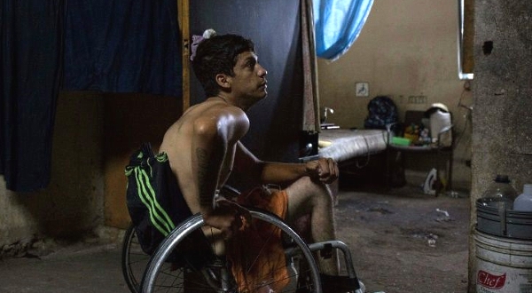 Johan Medina sits in his wheelchair by his room at a shelter located in the basement of the Sudameris public building in Caracas. AFP