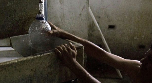 Johan Medina collects water from a pipe at a shelter located in the basement of the Sudameris public building in Caracas. AFP