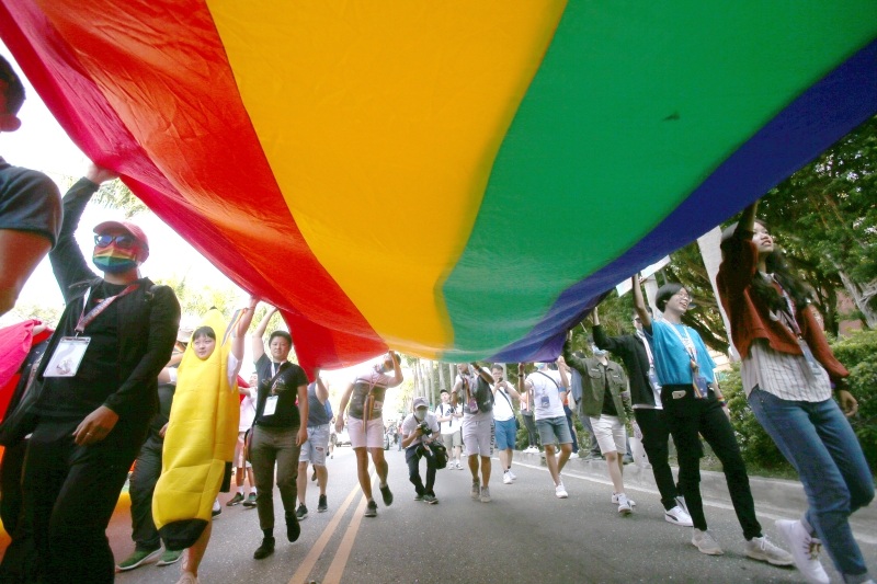 游行者高举巨大彩虹旗穿越街道。（图：美联社）