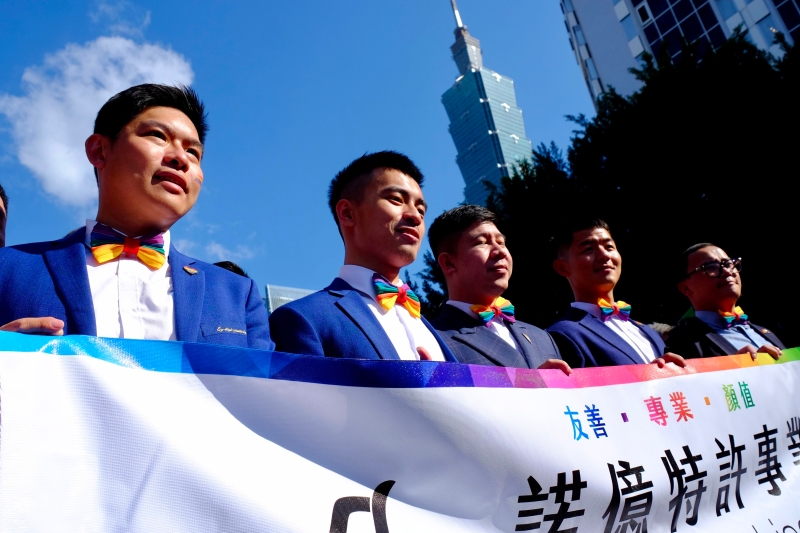 众人士戴着彩虹领结在台北101商业大楼前游行　 图：法新社