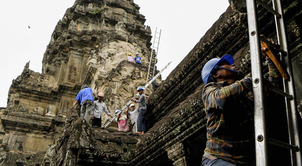 Gardeners climb up the exterior of Angkor Wat to remove tree saplings growing on it. AFP Gardeners climb up the exterior of Angkor Wat to remove tree saplings growing on it. AFP