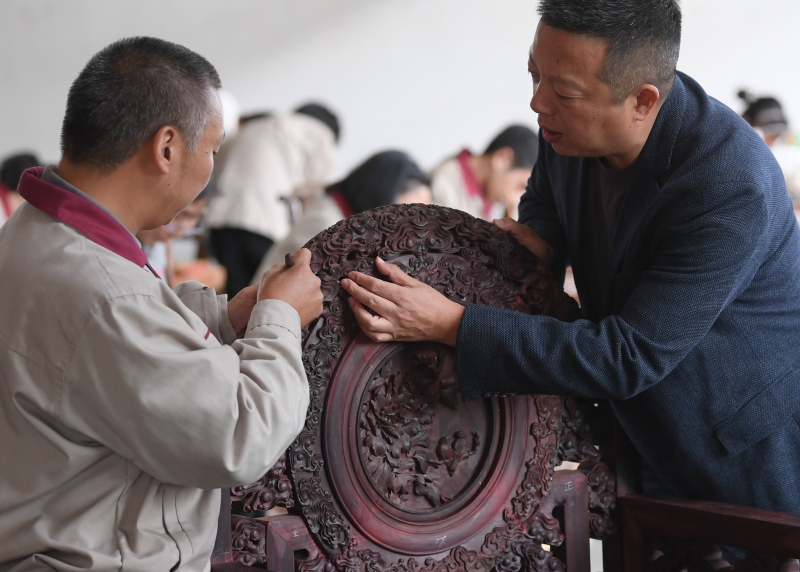 浙江省工艺美术大师张向荣与工作人员交流雕刻细节。

