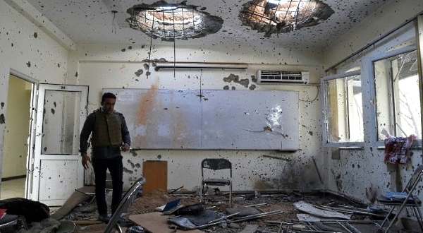 A journalist walks inside a damaged classroom a day after gunmen stormed Kabul university.