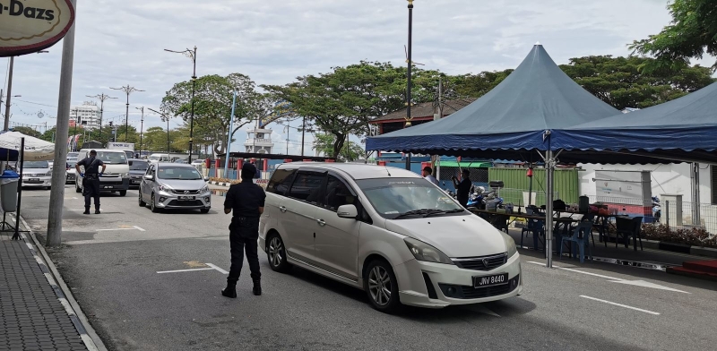 麻坡警方在麻桥往市区路段设置路障，检查驶入麻县的车辆。