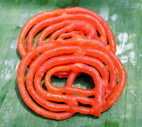 Gilebi也有人称为Jalebi。这亮得发光的橙色甜点有个可爱的昵称，叫“印度糖耳朵”，将调制好的面糊，在油锅之中拉成堆叠的圈形，起锅后浸泡在糖浆里。咬一口，还能看到里头有些许的糖浆流出来，堪称“甜度爆表”的印度甜食之一。