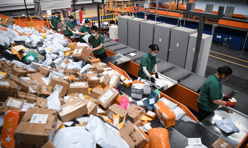 在双十一前夕，工作人员在中国邮政集团广州航空邮件处理中心内漏夜工作，在分拣机的帮助下进行供包作业。（图：新华社）