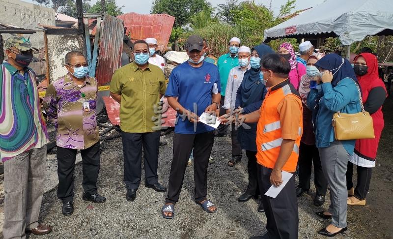 莫哈末沙努西（左三）巡视灾区后，也移交拨款给予灾民。