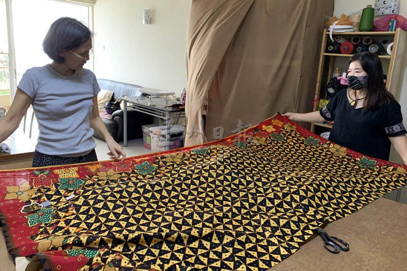 马如玉（右）和裁缝师摊开一匹峇迪布，讨论着要制成什么款式的旗袍。