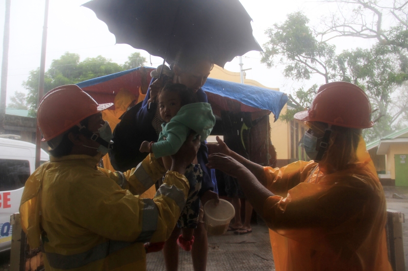 拯救人员帮忙将一对母女抬下，以暂时在疏散中心避难。（图：法新社）