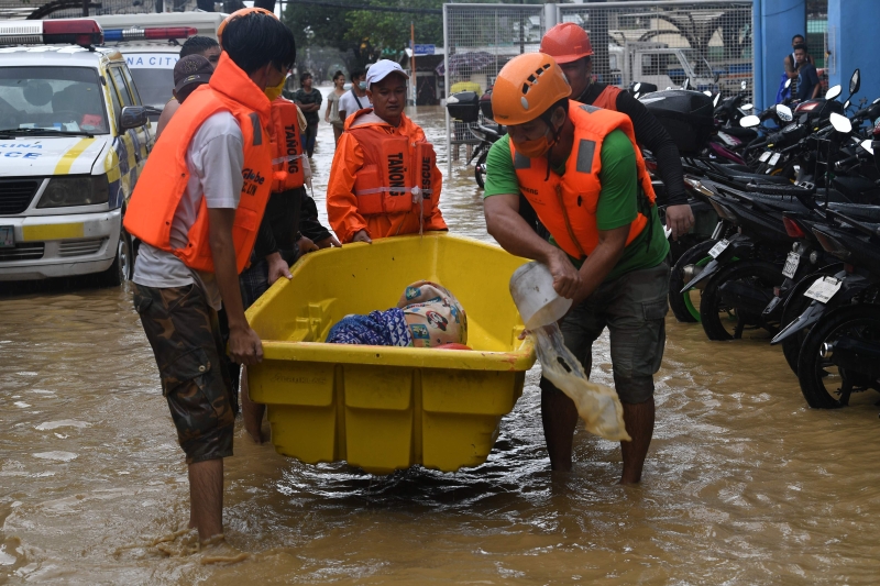 救护人员协助年迈的灾民离开重灾区。（图：法新社）