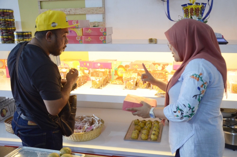华娜（右）亲自给顾客讲解月饼的由来，以及各种月饼的口味，让穆斯林顾客更了解友族。

