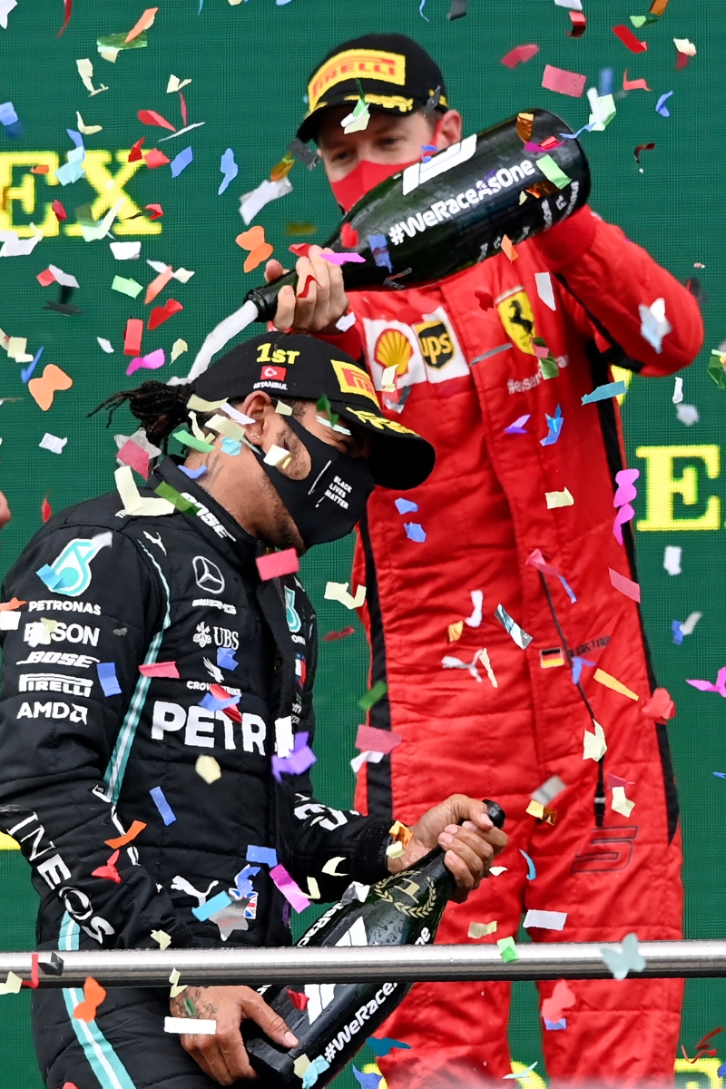 得益于队友勒克莱尔失误，维特尔（右）最终在F1土耳其站以季军完赛，这赛季首度登上颁奖台。图为维特尔在颁奖典礼向汉密尔顿（左）浇香槟致贺。（美联社照片）