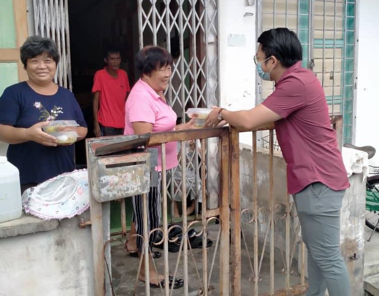 李政贤（右）协助把热心人士赞助的饭盒送给有需要的家庭。