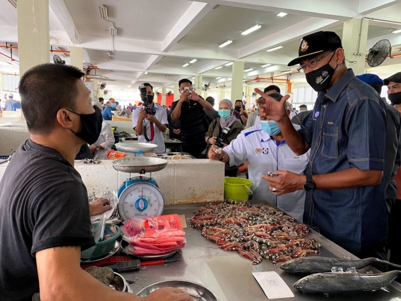 罗索华希（右一）向一名售卖鱼虾的商贩了解虾的价格与产地。