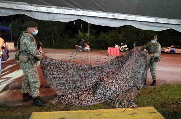 值勤军人在收拾防绑上帐蓬边的迷彩布。