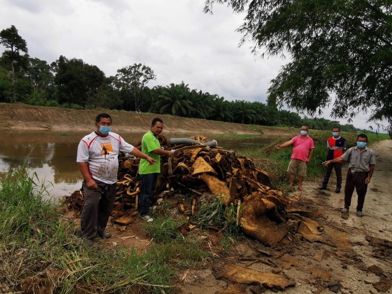周亚玖（左起）、莫哈末哈密、郑振山及陈锦指著被丢弃河旁的海绵废料；后为固体废料管理机构执法人员。