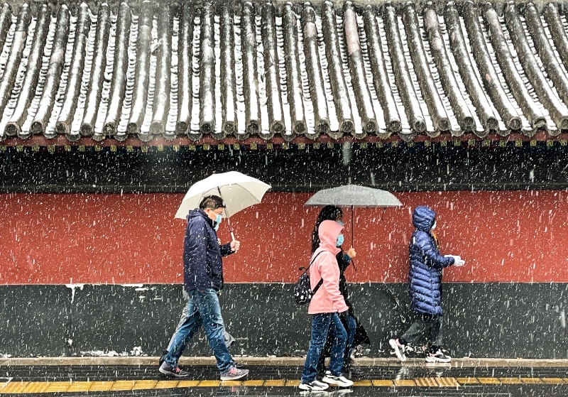 雪花飘飘，行人走在北京雍和宫大街上。　

