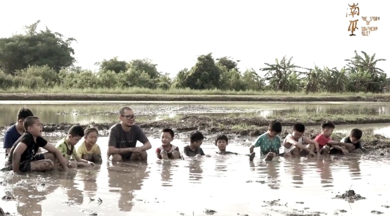 张吉安引领一群小演员，坐在稻田淤泥里唱民谣。（图取自张吉安脸书）