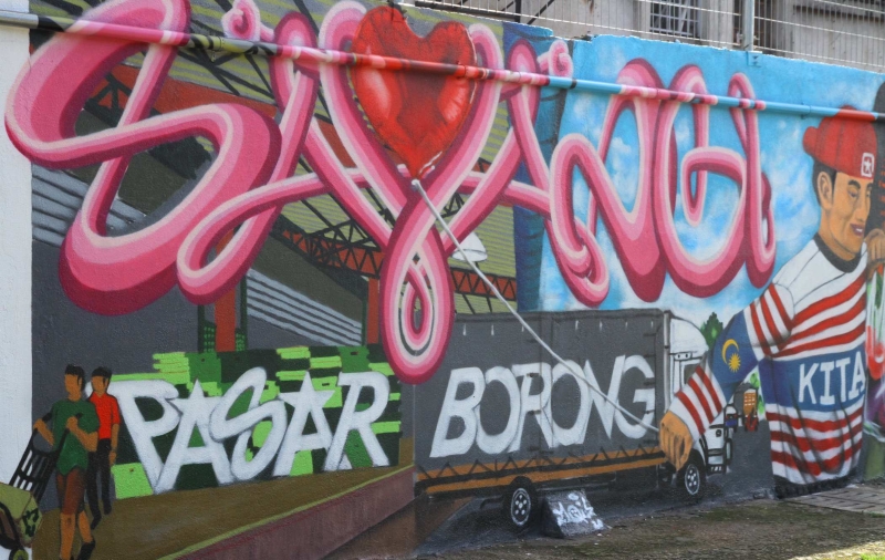艺术家将比赛主题“Sayangi Pasar Borong Kita”涂鸦在墙壁上。
