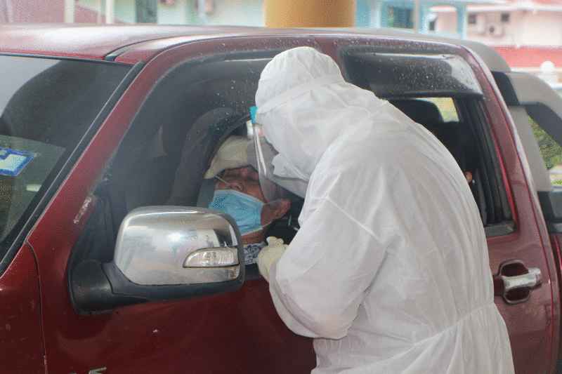 医护人员为坐在车内的一名乘客进行冠病筛检。