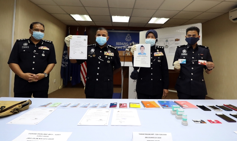 阿育汉（左二）展示警方所起获的银行提款卡、存折和公司注册文件等。