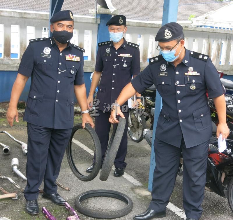 奥斯曼（左）及副警区主任拉兹兰（右）展示飙车者使用的脚车轮胎，中为交警主任吴伟文。
