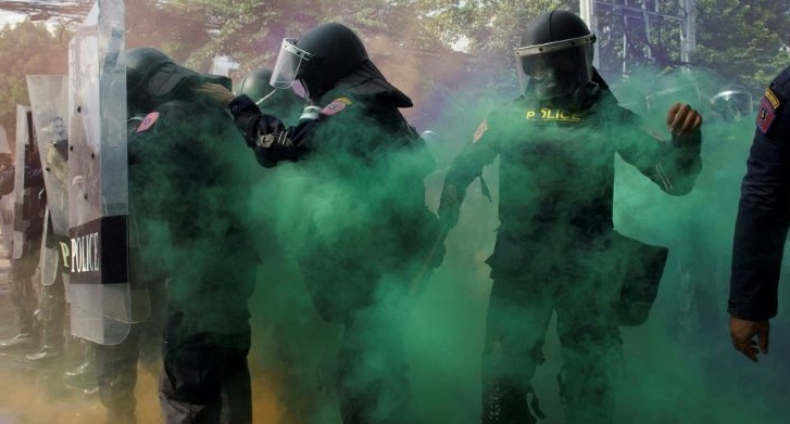 Green smoke engulfs a line of police near parliament in Bangkok. AFP
