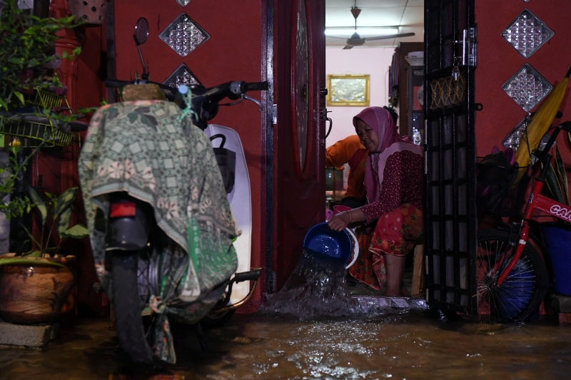 积水开始淹进住家，居民赶紧用容器把水倒出去。