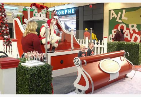 美国达拉斯一家购物中心举办“雪天达拉斯”活动，迎接圣诞节。两名儿童和戴著防护面罩的“圣诞老人”保持社交距离合影。