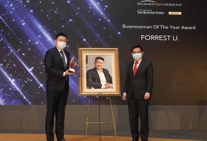 李小冬（左）获颁2020年度“新加坡商业奖”的“年度杰出商人奖”。他在颁奖礼上，从王瑞杰手中接过了奖杯。主办方也赠送李小冬一幅个人肖像画作为纪念。（联合早报照片）