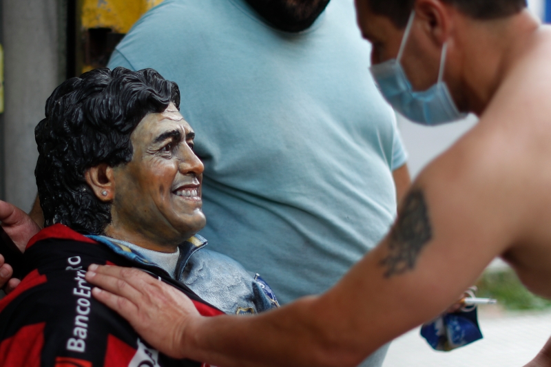 阿根廷球迷手触碰马拉纳多的肖像，回忆球王当年的辉煌史。