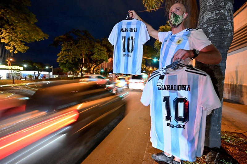 在哥伦比亚，一名男子在街道旁兜售马拉多纳生前穿过的10号球衣。