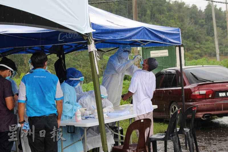 尽管下着大雨，仍无阻卫生局人员坚守岗位，为民众进行冠病筛检。 