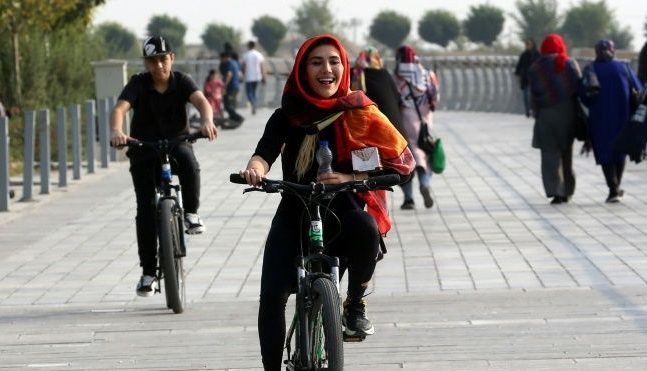 A woman rides a bicycle around Chitgar Lake in Tehran. AFP