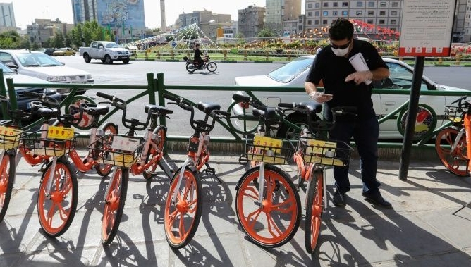 A man uses his phone to unlock a bicycle of bike-sharing service Bdood at Valiasr Square in Tehran. AFP