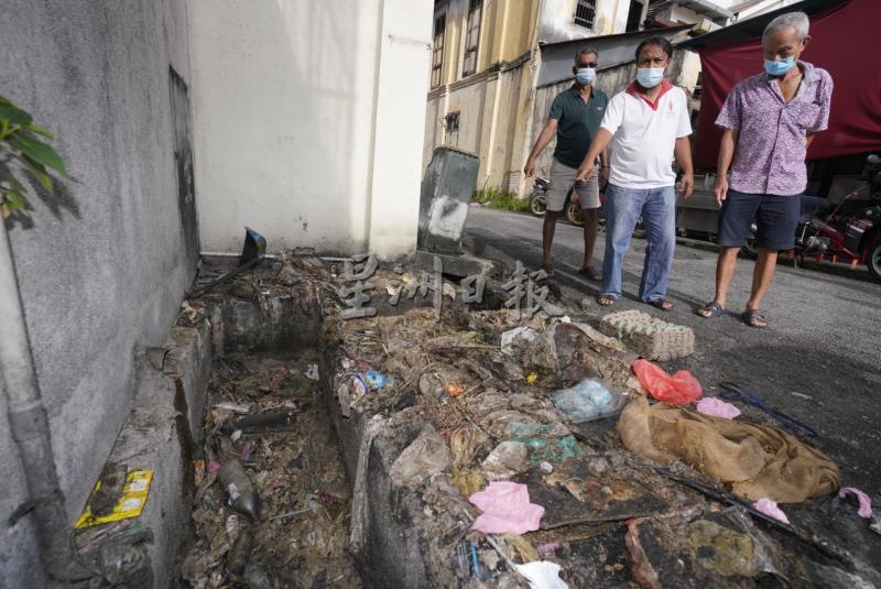 后巷沟渠与路上充满垃圾，罗斯兰（中）等人指著垃圾促请市政厅尽快清理；左是纳能德拉，右是陈景贤。