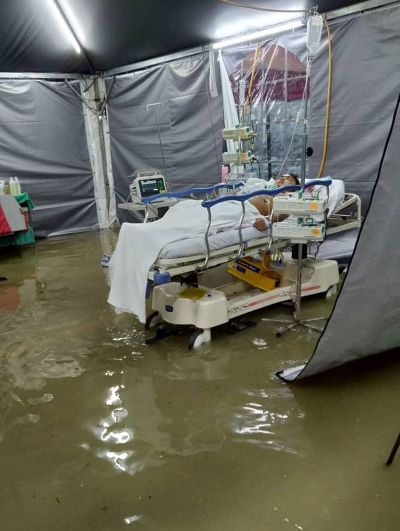 在临时帐篷内就医的病人只能躺在被泡在水里的病床上。
