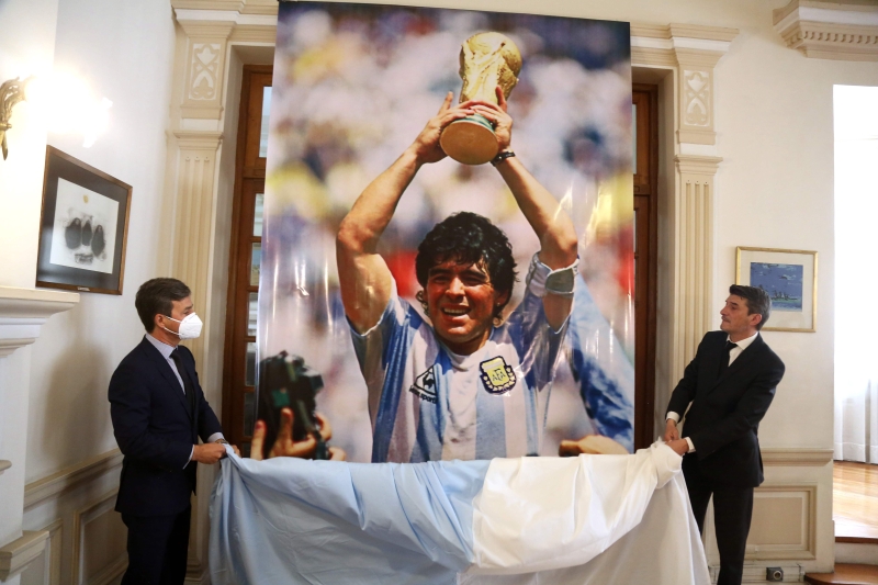 阿根廷大使馆负责人迭戈·阿隆佐（右）在27日向已故足球传奇马拉多纳致敬时，揭开其赢得1986年世界杯时的照片。（法新社照片）