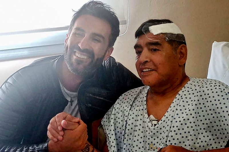 马拉多纳（右）在11月初完成脑血栓手术还与私人医生卢克握手开心合照，却没想到后者如今却被老马家属以失职害死病人提告。（法新社照片）