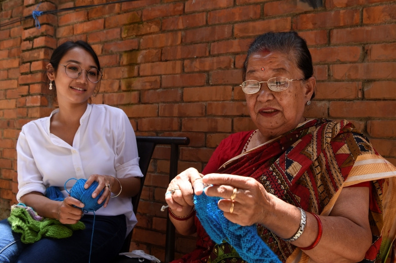 尼泊尔女子罗琳娜（左) 从小穿着祖母(右）亲手织的新袜子，为脚丫子保暖。为了推广这些充满人情味及温度的传统手工针织品 ， 她创办了一家手工艺企业，协助家乡的妇女售卖这些手工制品 。（法新社照片）