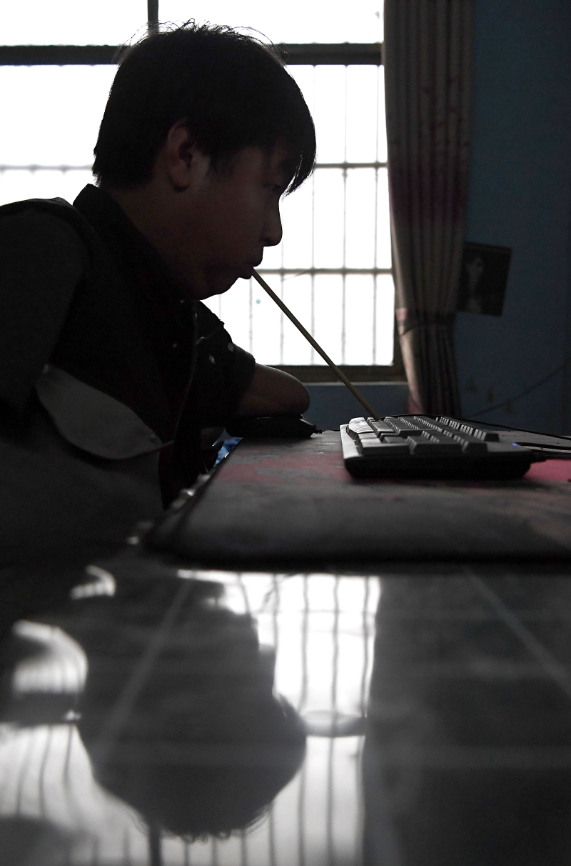 孙亚辉直播时用嘴含着筷子敲打键盘和网民交流。（图：新华社）