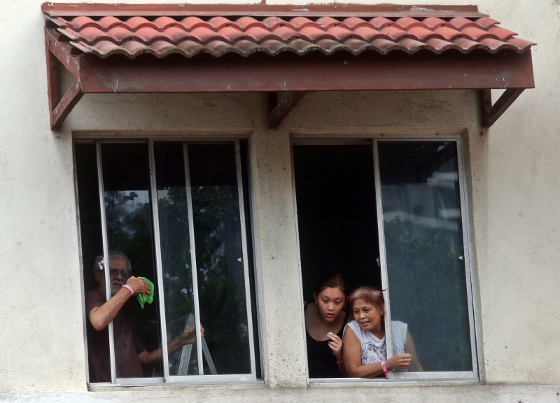 有的居民从住家的窗口瞭望公寓外的情况，而且居民的手上皆戴着粉红色隔离手环。