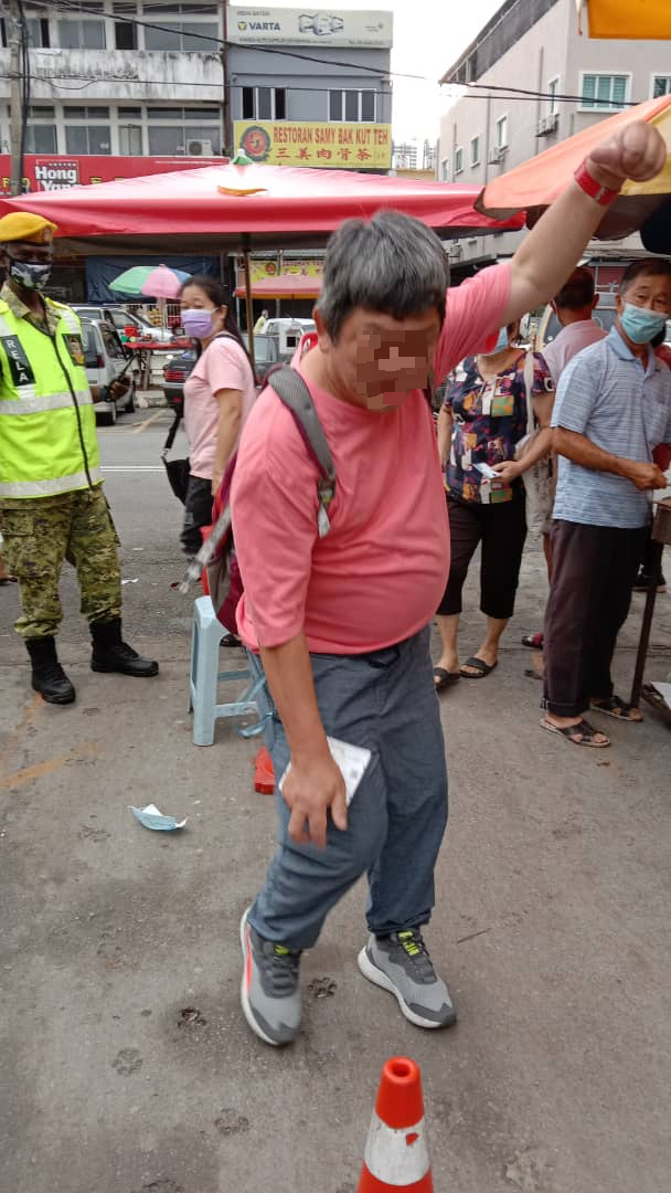 一名中年的残障人士因不满自己不获进入巴刹售卖彩票，而随手拿起路锥扔向一名女志愿警卫。（照片由余保凭提供）